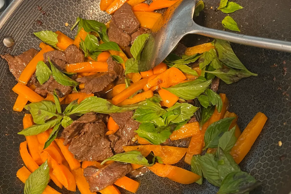 Beef, peppers, and Thai basil all tossed together in the wok, the basil just starting to wilt.